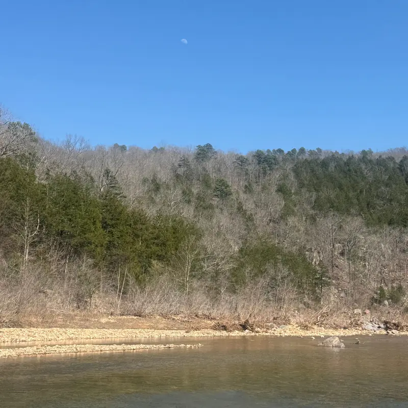 River bend beneath forested hillsides — a living reflection of enduring tradition